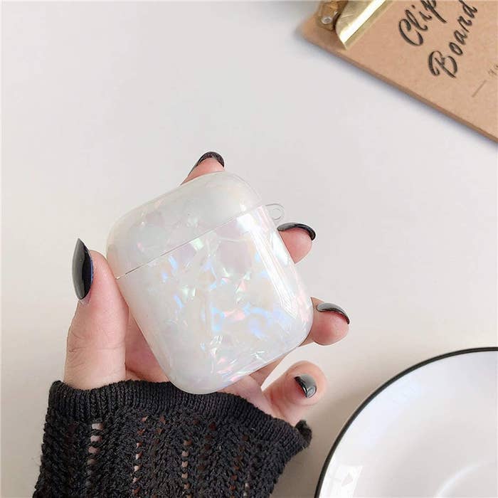 Model holding white iridescent AirPods case 