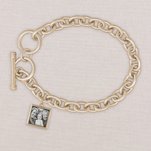 a gold charm bracelet with a picture in a square charm
