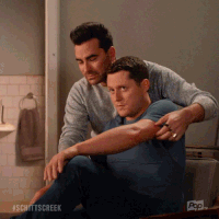 a gif of david and patrick from schitt&#x27;s creek posing for a photo