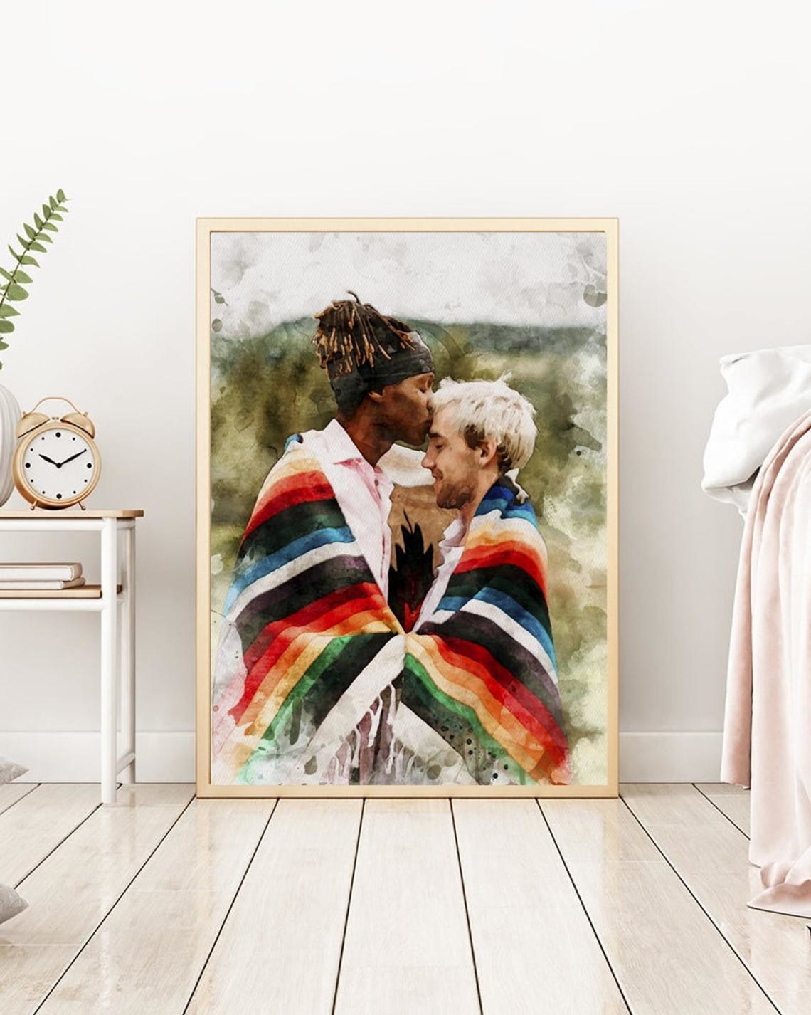 A couple wrapped in a blanket, one kissing the other's forehead, in a watercolor print