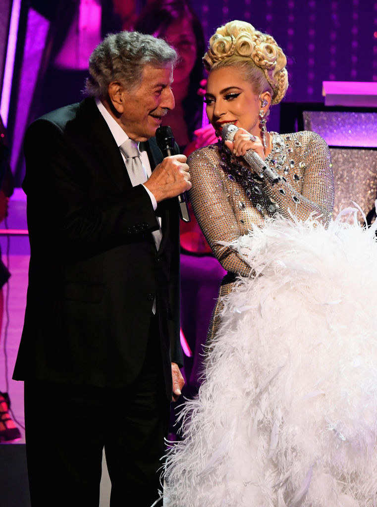 Tony Bennett wears a sharp suit and Lady Gaga wears a beautiful dress as they sing close together 