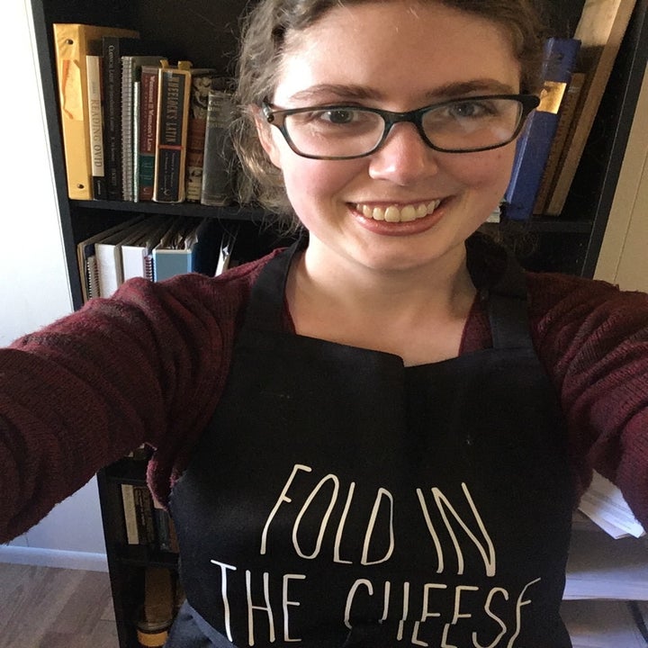 Abby wearing the black apron that reads "Fold in the cheese" in white text