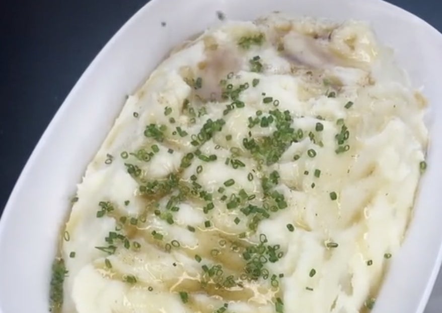 A serving dish of mashed potatoes with green garnish