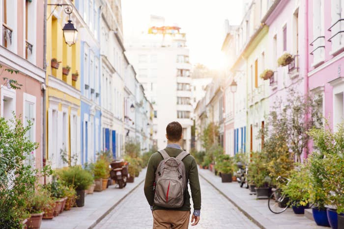 A man with a backpack walks down a pretty, foreign street