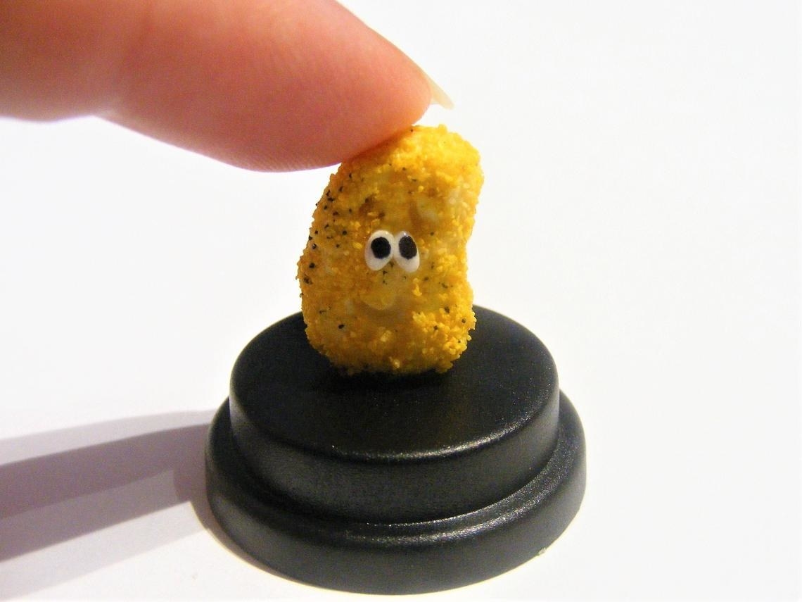 small chicken nugget with eyes on a black stand 