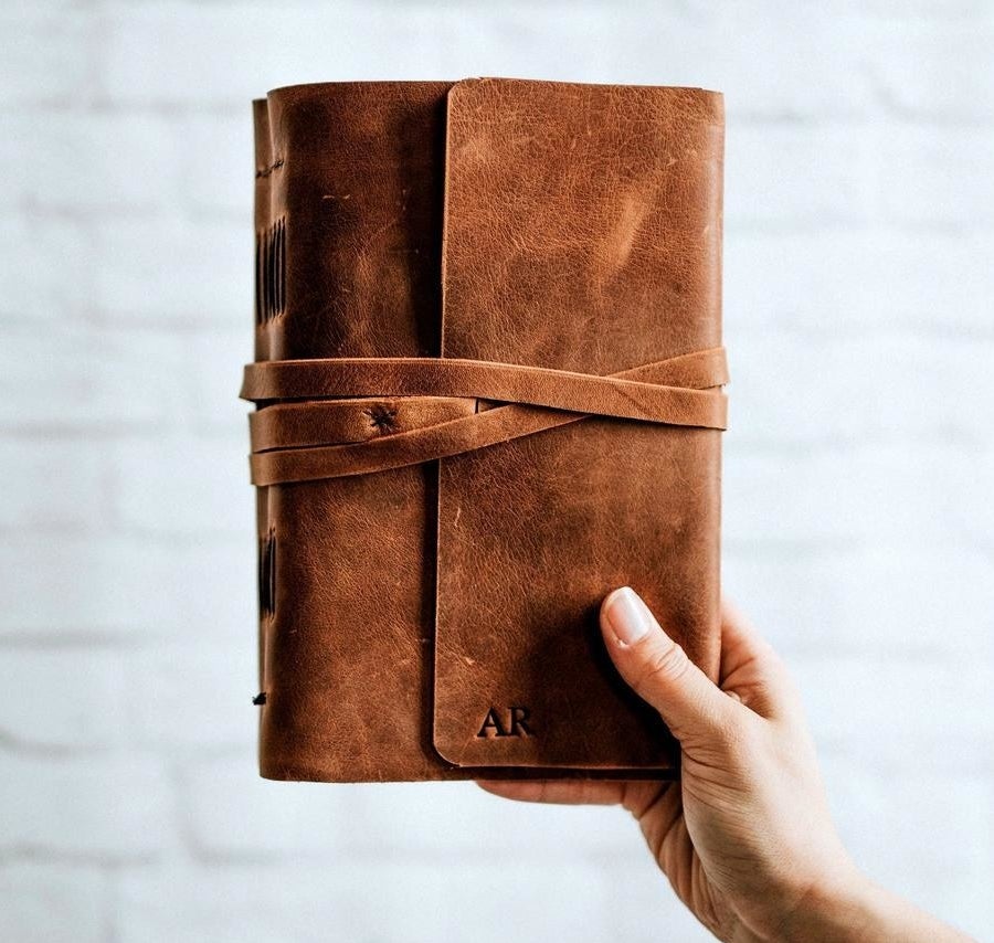 A person holding up a journal that is stamped with someone&#x27;s initials