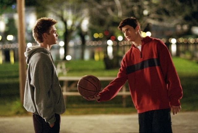 two teenage boys wearing hoodies are playing basketball outside 