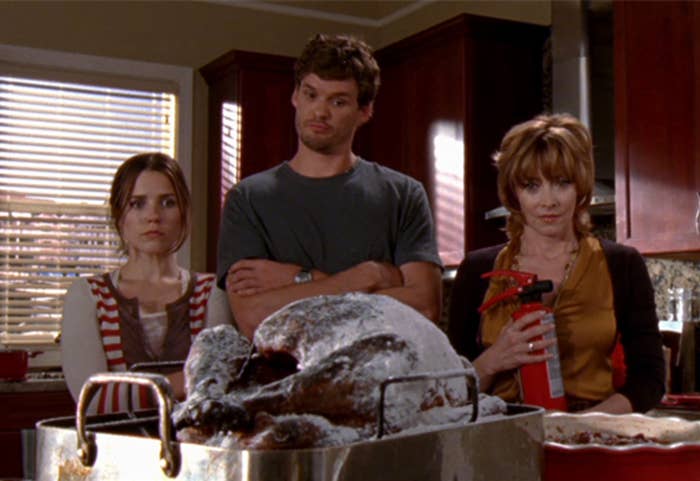 three people have their arms crossed while they look at an uncooked turkey