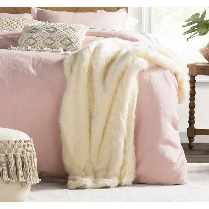 white faux fur blanket draped on a bed