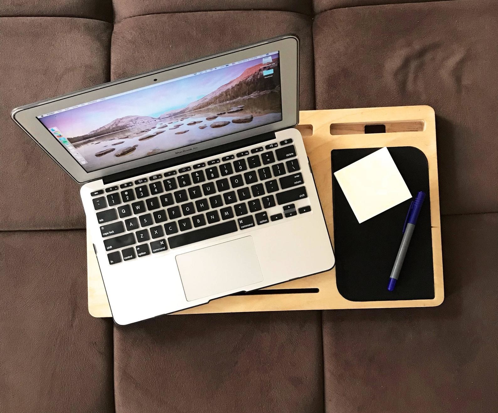 a laptop and notepad with pen on wooden tray