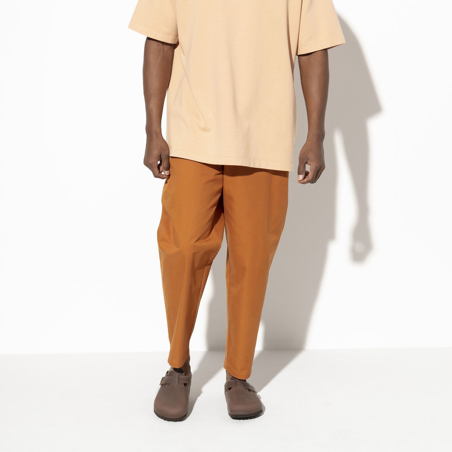 Model wearing Birkenstocks with orange pants 