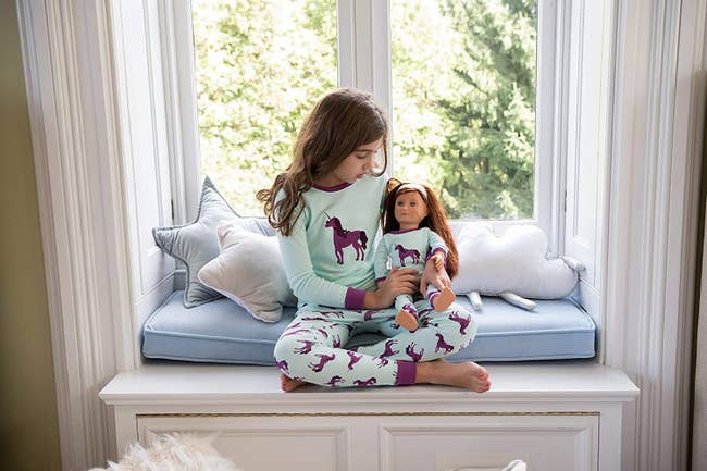 a child and her doll in matching unicorn pajamas
