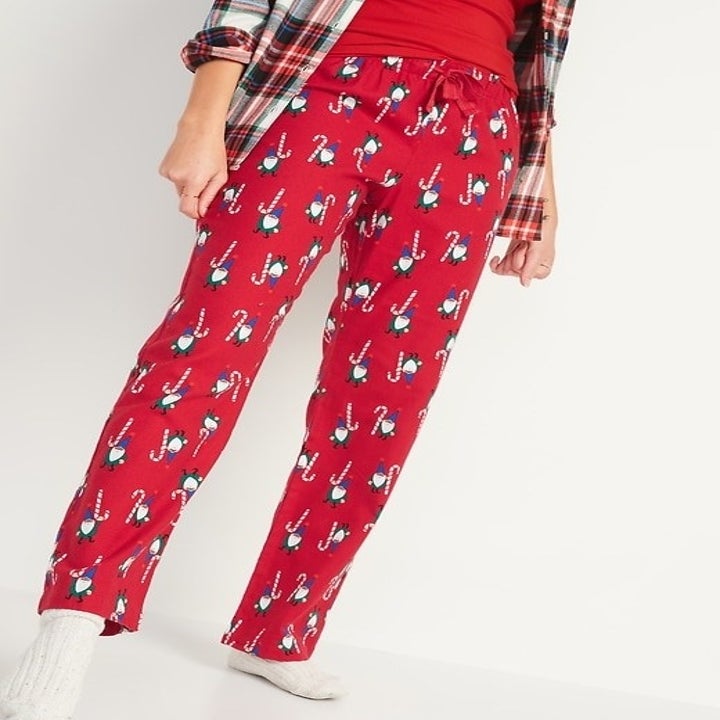 a model in red pajama flannel pants with a candy cane design and elves on them