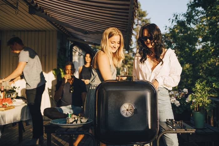 Group of friends hanging around a BBQ in the fading sun