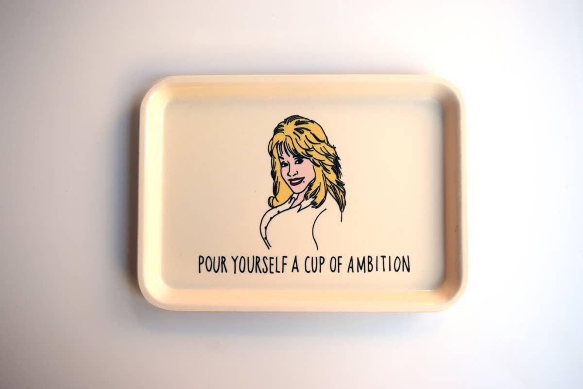 The beige tray with an illustration of Dolly and text &quot;Pour yourself a cup of ambition&quot;