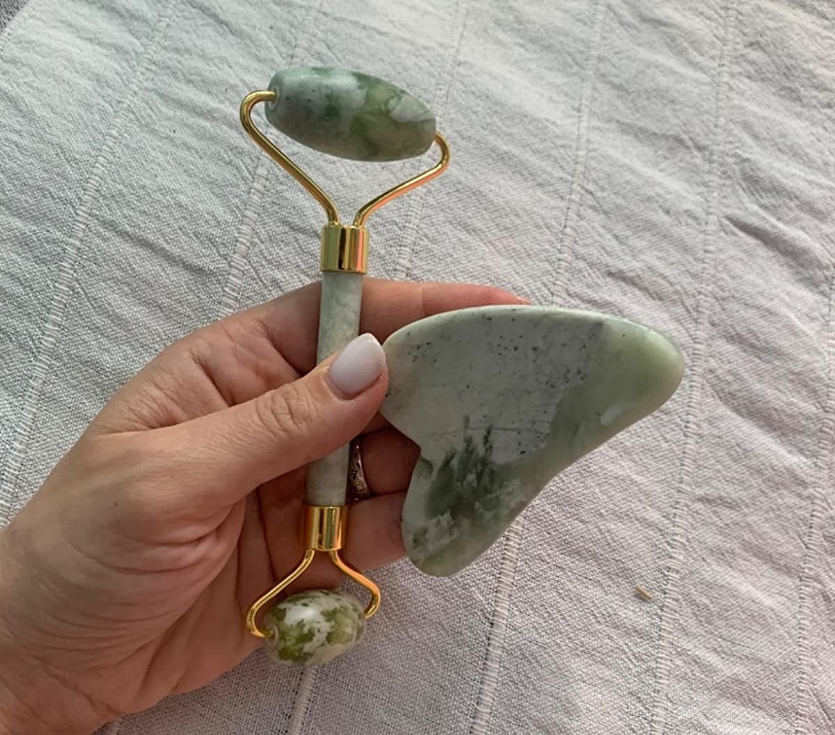 A reviewer holding the green double-sided roller and gua sha