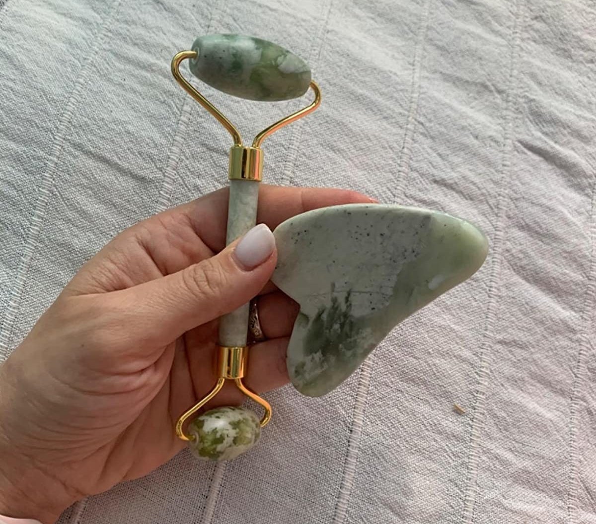 A reviewer holding the green double-sided roller and gua sha