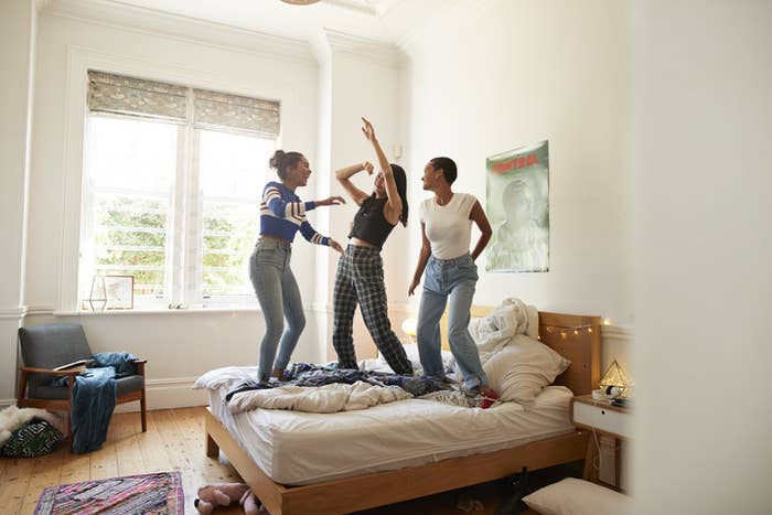 Three people standing and dancing on a bed