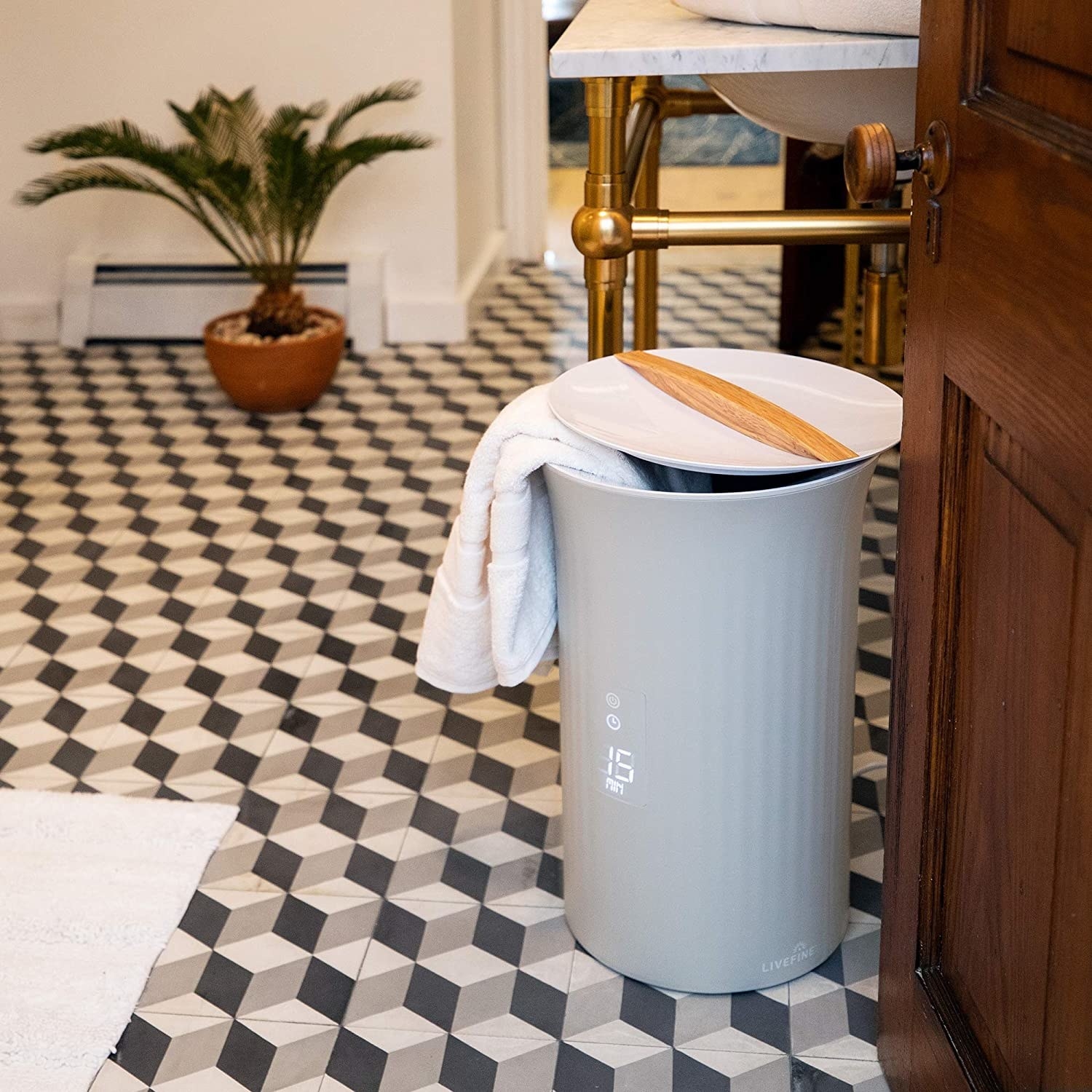 The circular-shaped bin in grey with a lid and wood handle and a small screen on the front