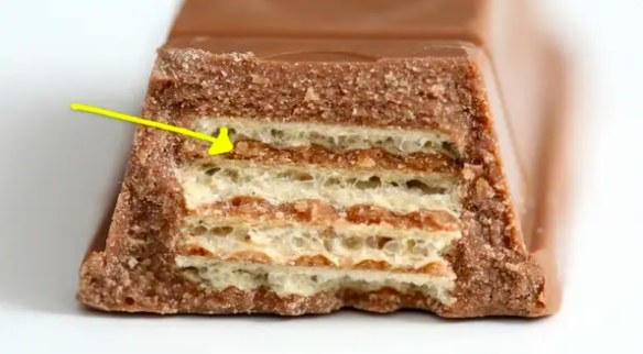 Broken bar of Kit Kat with yellow arrow pointing to the filling