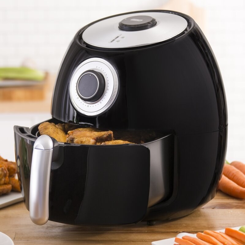 a black and silver air fryer with chicken wings inside