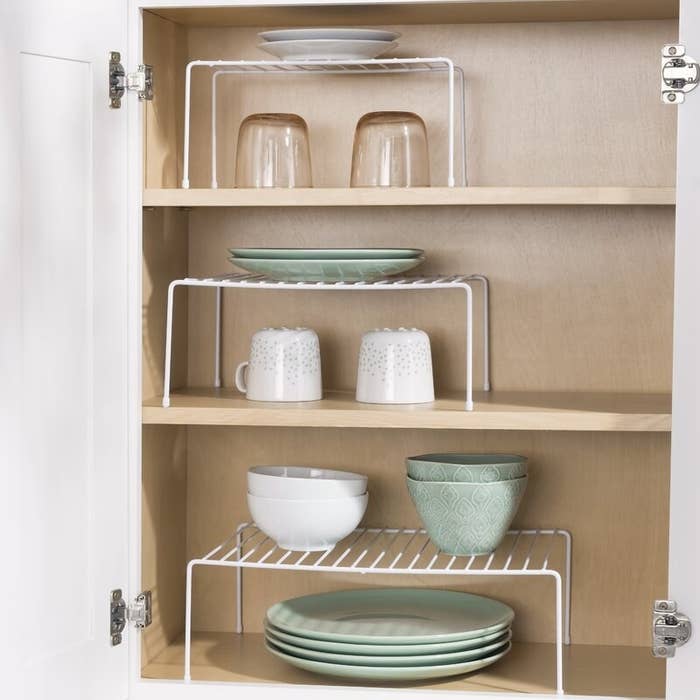 three white wire racks with plates on them on three different shelves