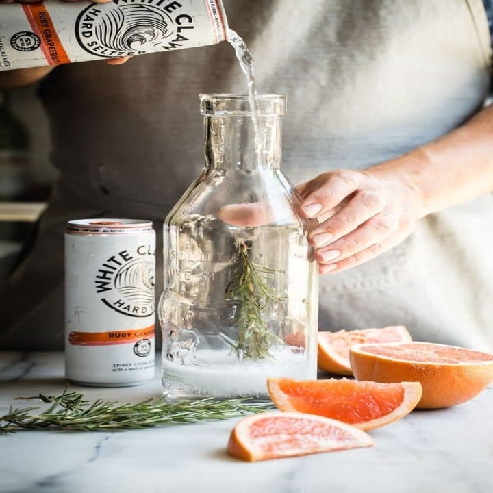 Pouring grapefruit white claw into a caraffe.