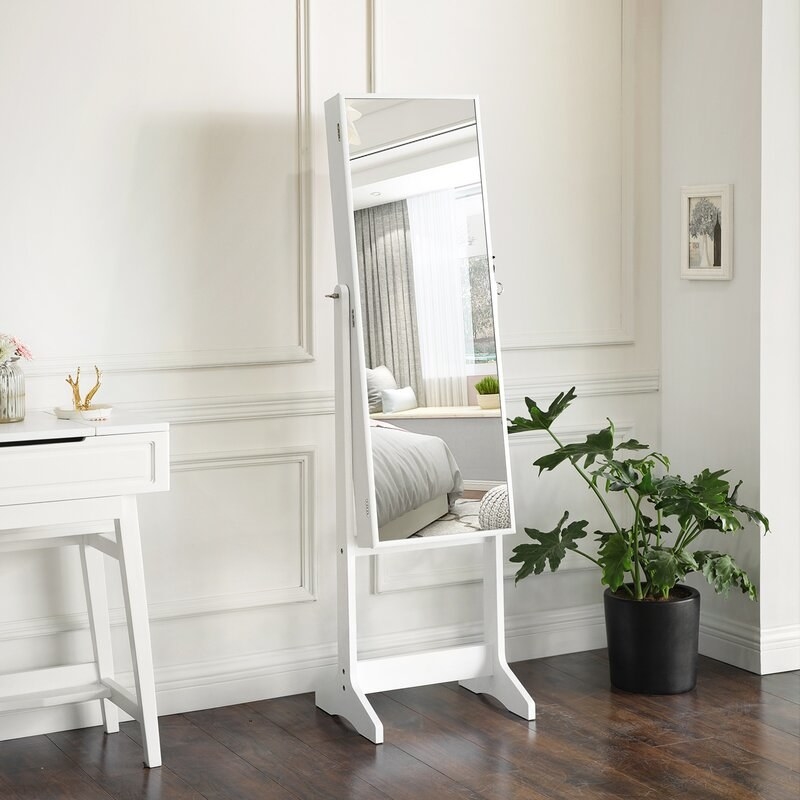 a white body mirror that opens up to a jewelry chest in a bedroom