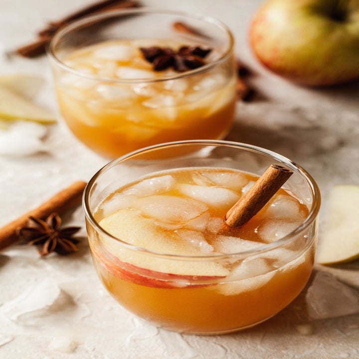 Two apple cider cocktails garnished with cinnamon sticks.