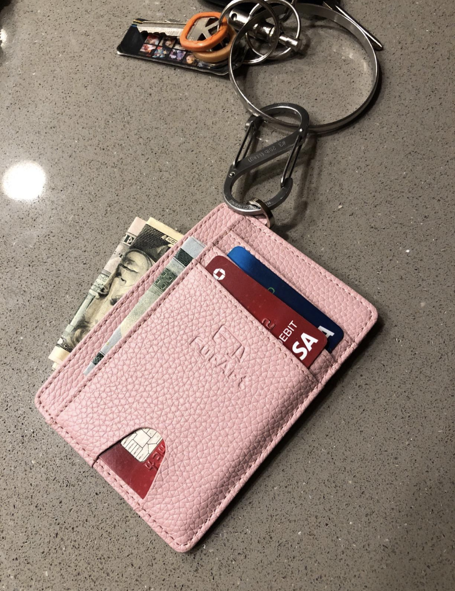 Reviewer image of flat pink wallet with credit cards and cash in it attached to a keychain 