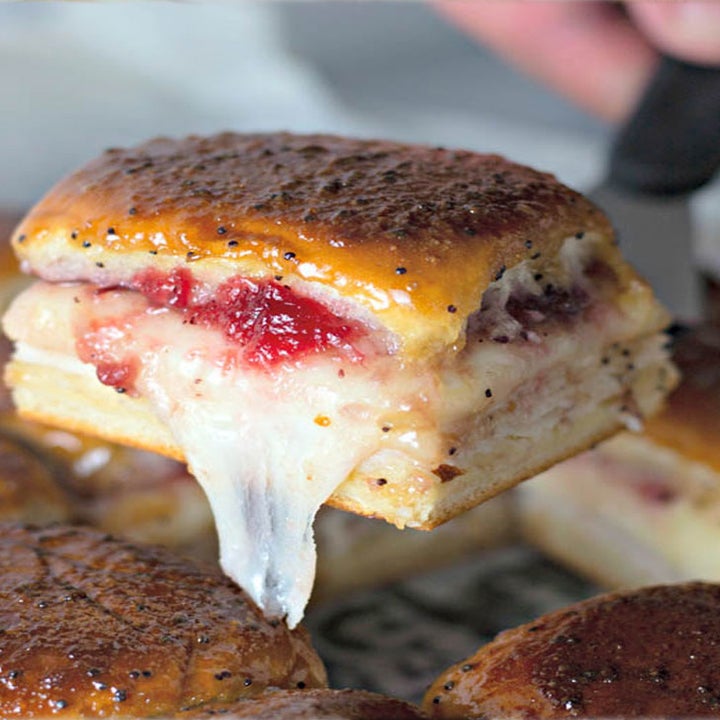 A spatula holding a baked turkey and cranberry slider with melted cheese.
