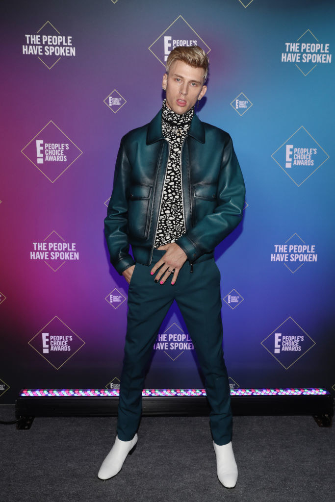 Machine Gun Kelly wears a slightly distressed leather jacket with pants in a matching color and a patterned turtleneck top