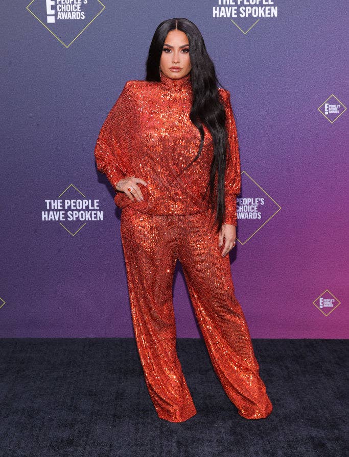 Demi Lovato wears a sparkly high-neck top with matching loose-fitting pants