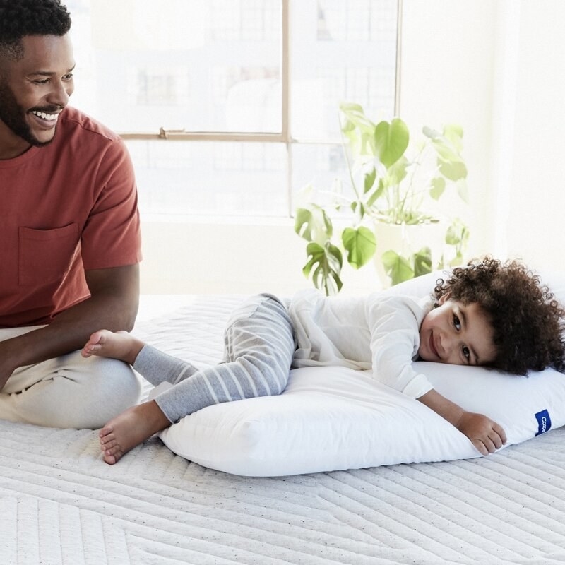 a child hugging a casper pillow on a bed