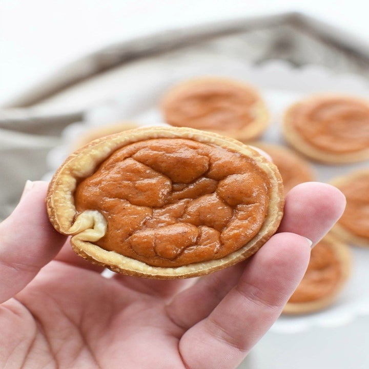 Someone holding a mini pumpkin pie.
