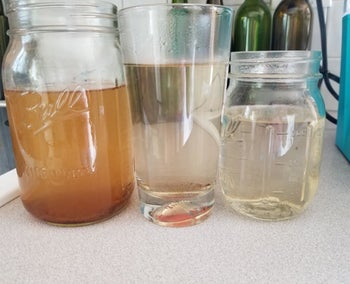 Three glass containers showing the progression of colored water to come out of machine. From brown water on the left to clean clear water on the right.