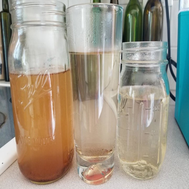 Three glass containers showing the progression of colored water to come out of machine. From brown water on the left to clean clear water on the right.