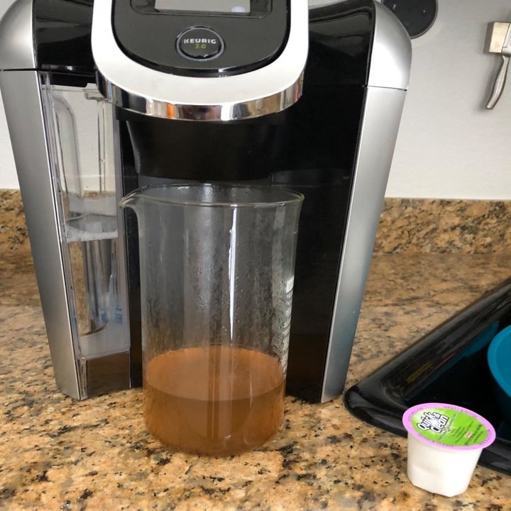 Reviewer image of beaker beneath Keurig showing the effects of cleaning pods with brown water coming out of machine.