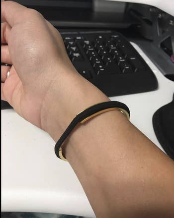 Reviewer wearing a gold bangle with a black hair tie in its grooves 