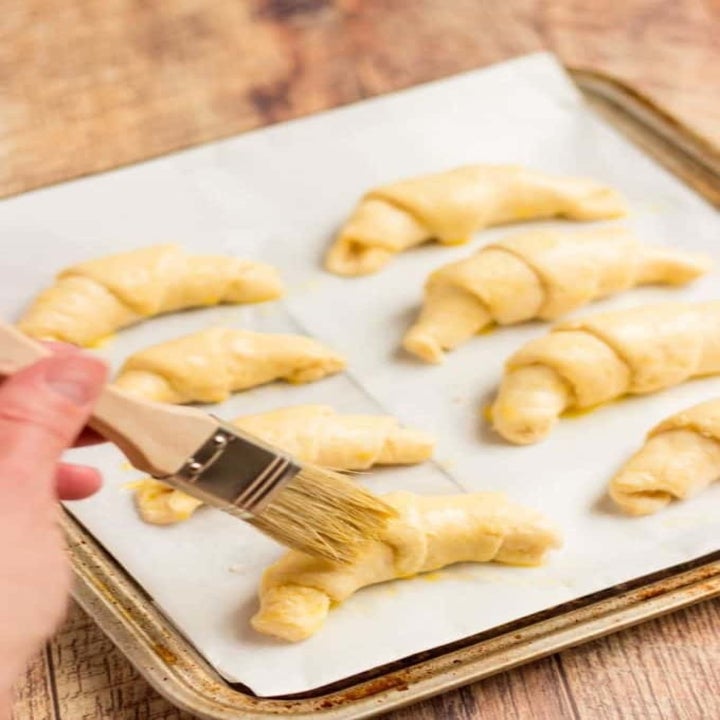 Brushing melted butter on the Brie crescent rolls.