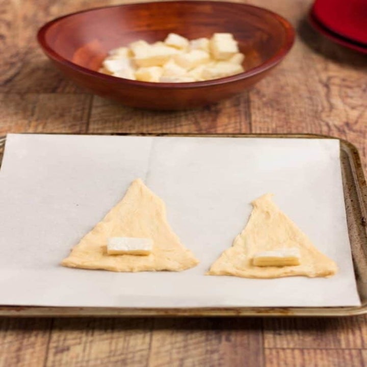 Two crescent roll squares with a slice of Brie cheese.