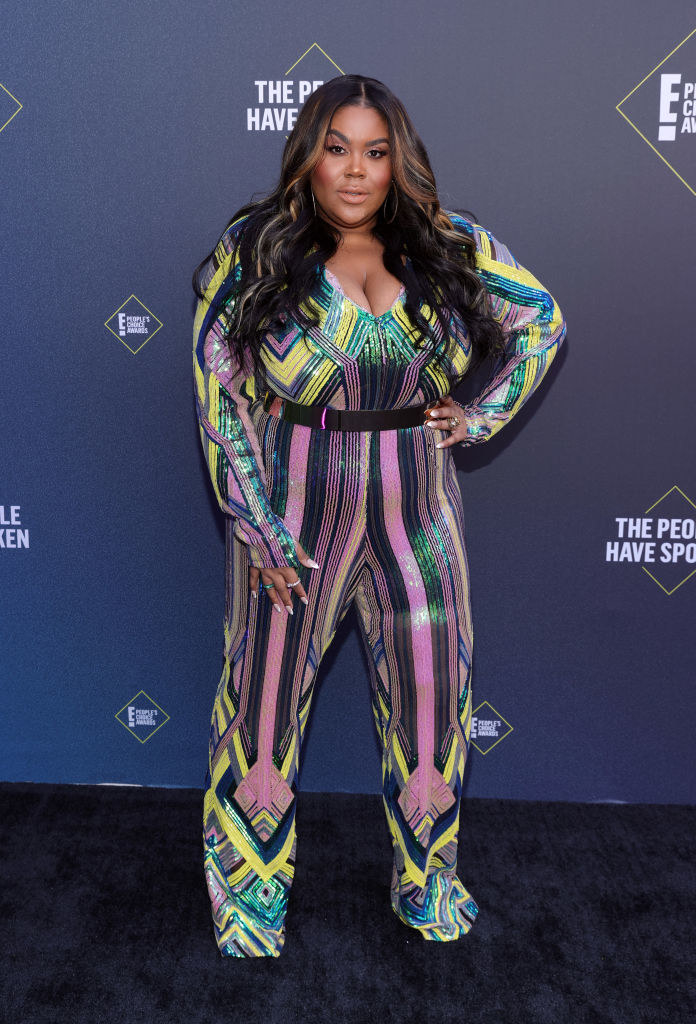 Nina Parker wears a shiny and brightly-colored jumpsuit that has a geometric pattern 