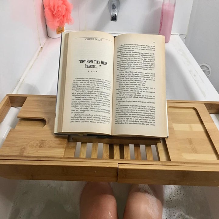 Reviewer reads book while using same bathtub caddy in tub