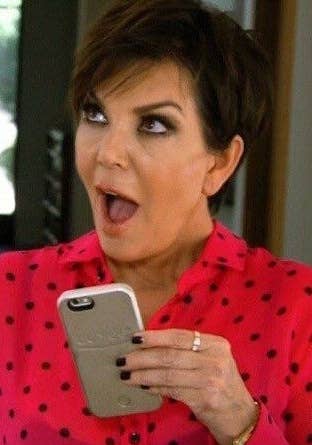 Kris Jenner holding a phone with a look of surprise on her face
