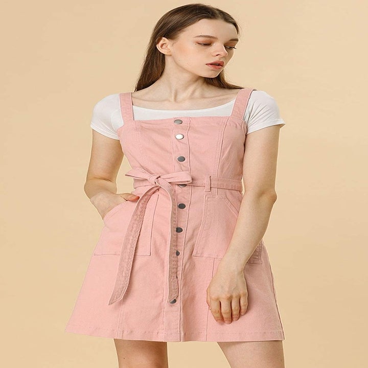 A model wearing the dress with a tie belt in pink over a tee