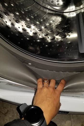 Reviewer showing the edges of a clean washing machine drum and encasement 