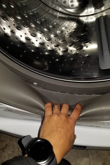 Reviewer showing the edges of a clean washing machine drum and encasement 
