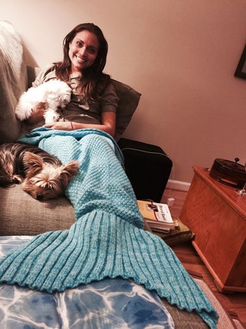 Reviewer snuggles with dog under a mermaid-shaped blue blanket at home