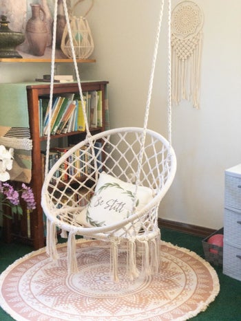 A reviewer's white macrame swing with a white pillow hanging up in a corner