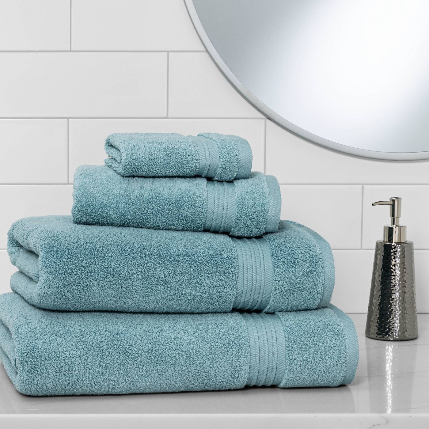 The spa bath towels in an aqua blue stacked on top of each other to show the differences in size